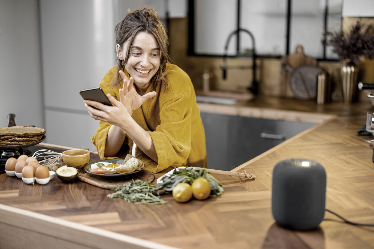 Woman speaking to a smart speaker during a breakfast at home