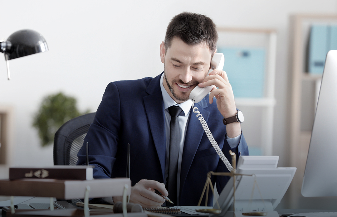 Junger Geschäftsmann mit VoIP-Telefon an seinem Bürotisch