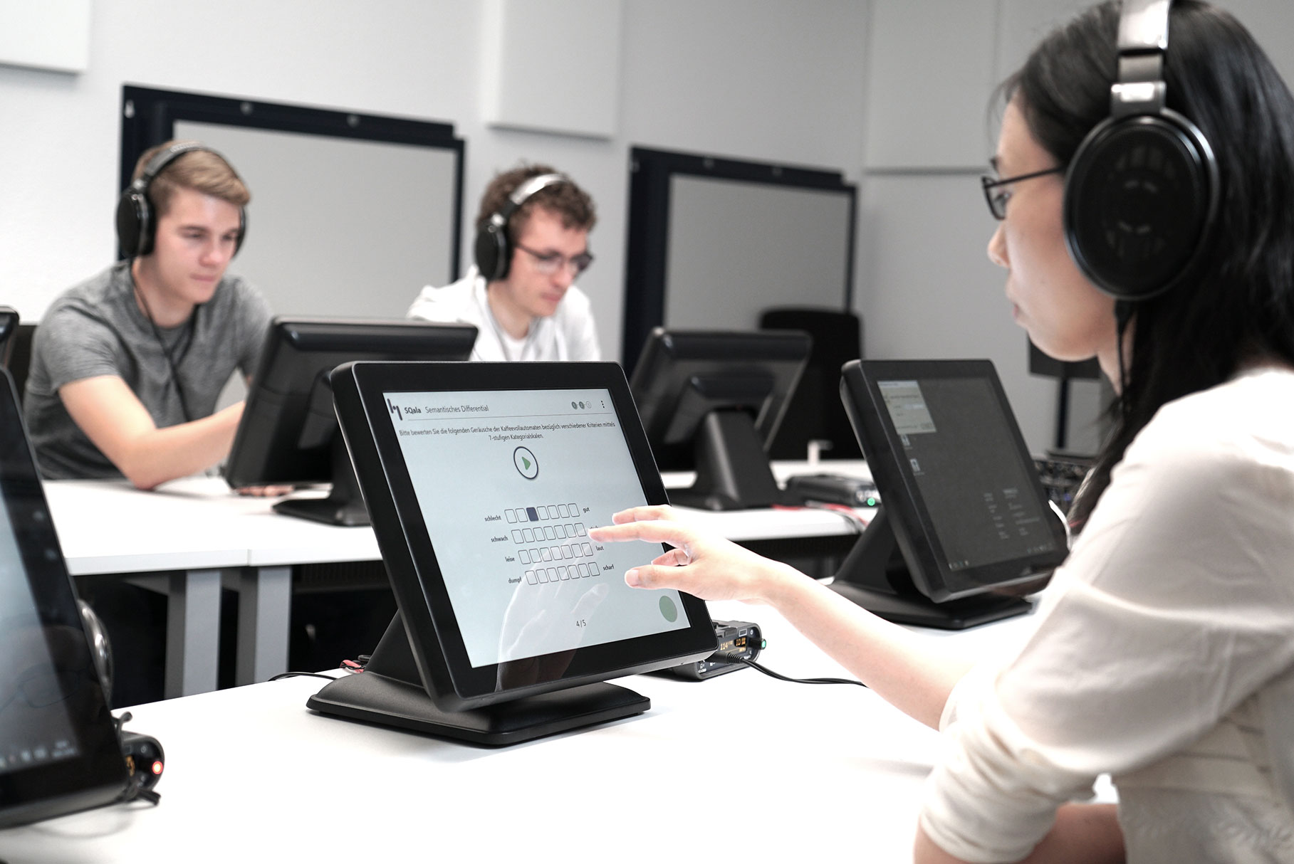 Three students working in a listening studio with SQala.